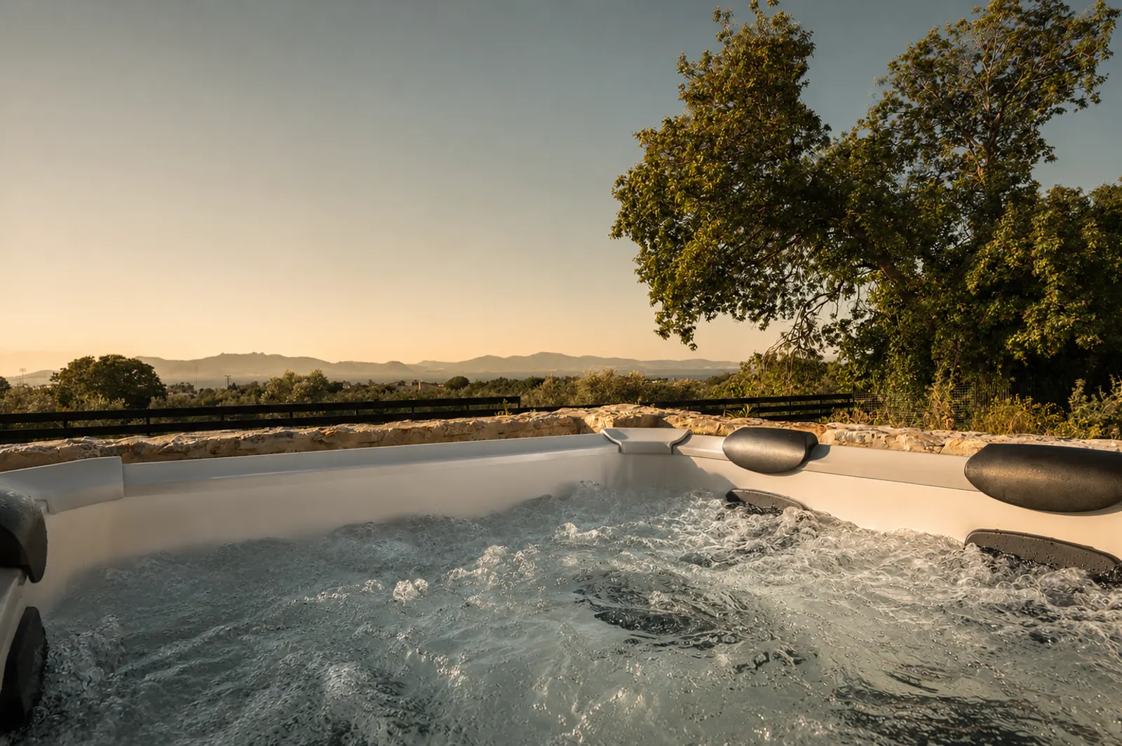 Private outdoor jacuzzi bubbling at golden hour with open views