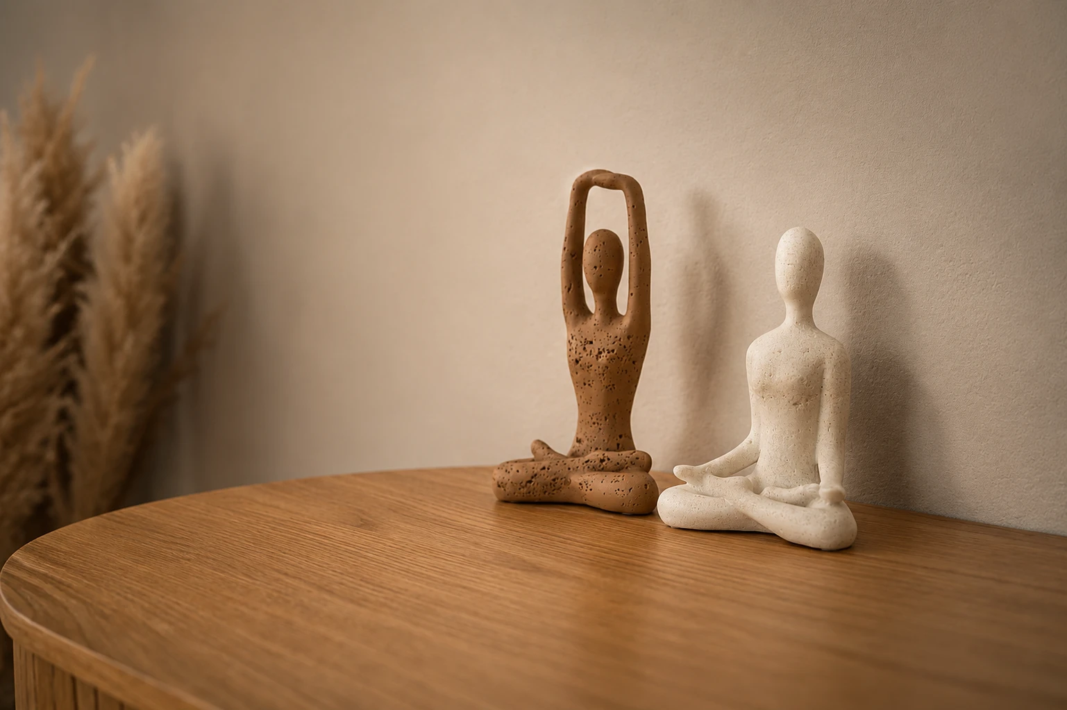 Two ceramic yoga figures on a wooden table inside an Ena & Ena home